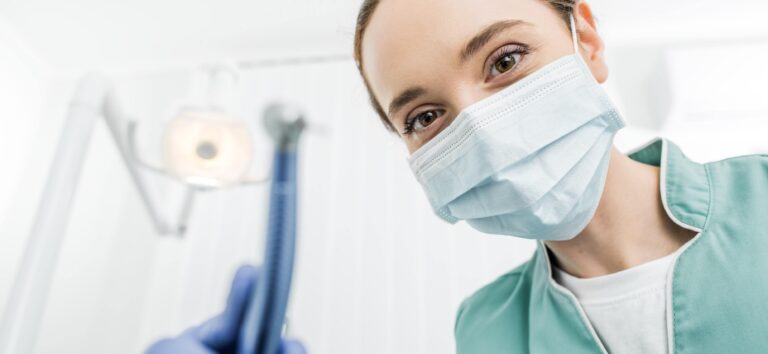 Próchnica Zębów - Dentystka w niebieskich rękawiczkach trzymająca narzędzia stomatologiczne, gotowa do leczenia próchnicy zębów